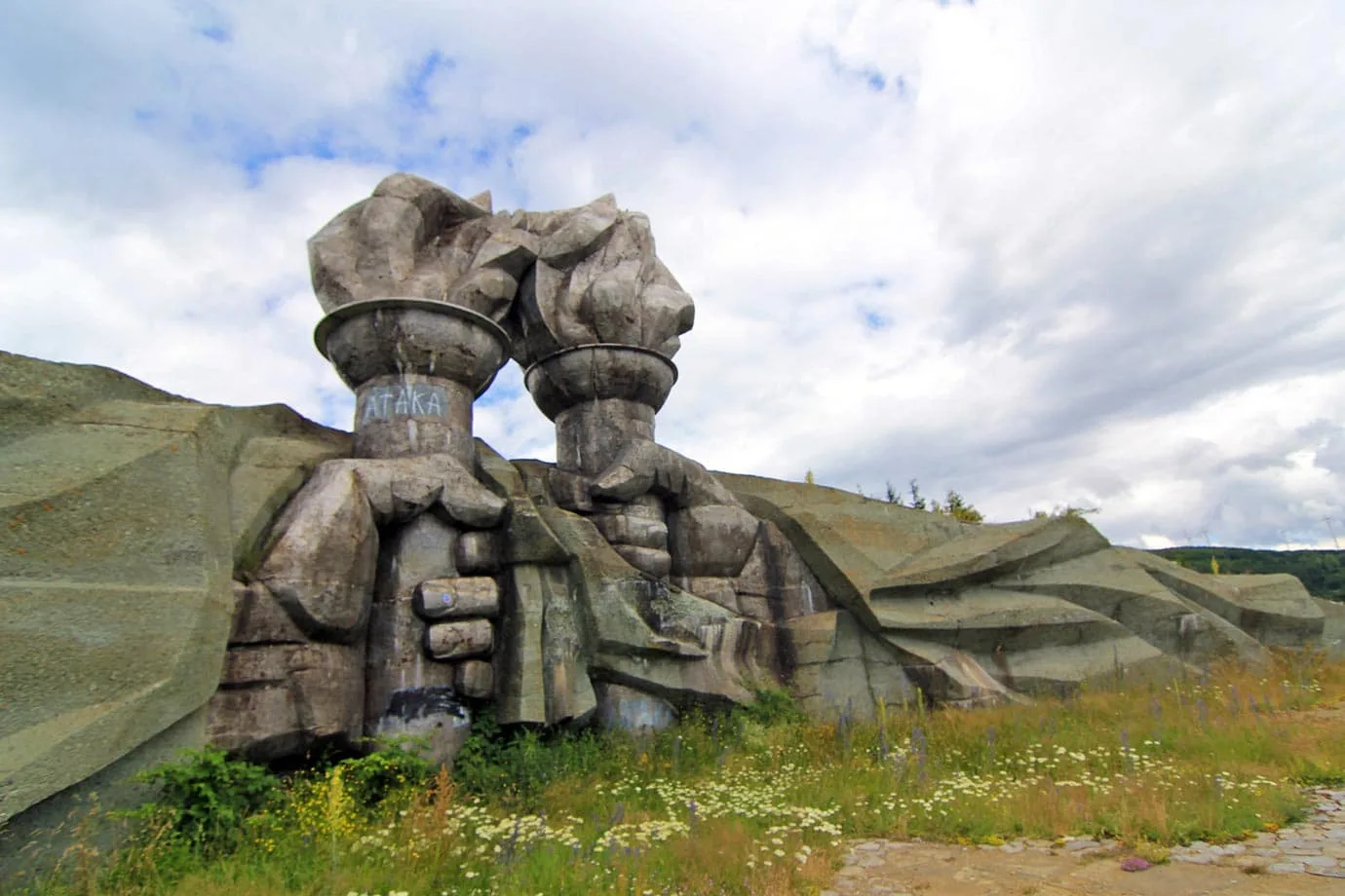 At the bottom of the hill at Buzludzha, two humongous fists holding flaming torches come together